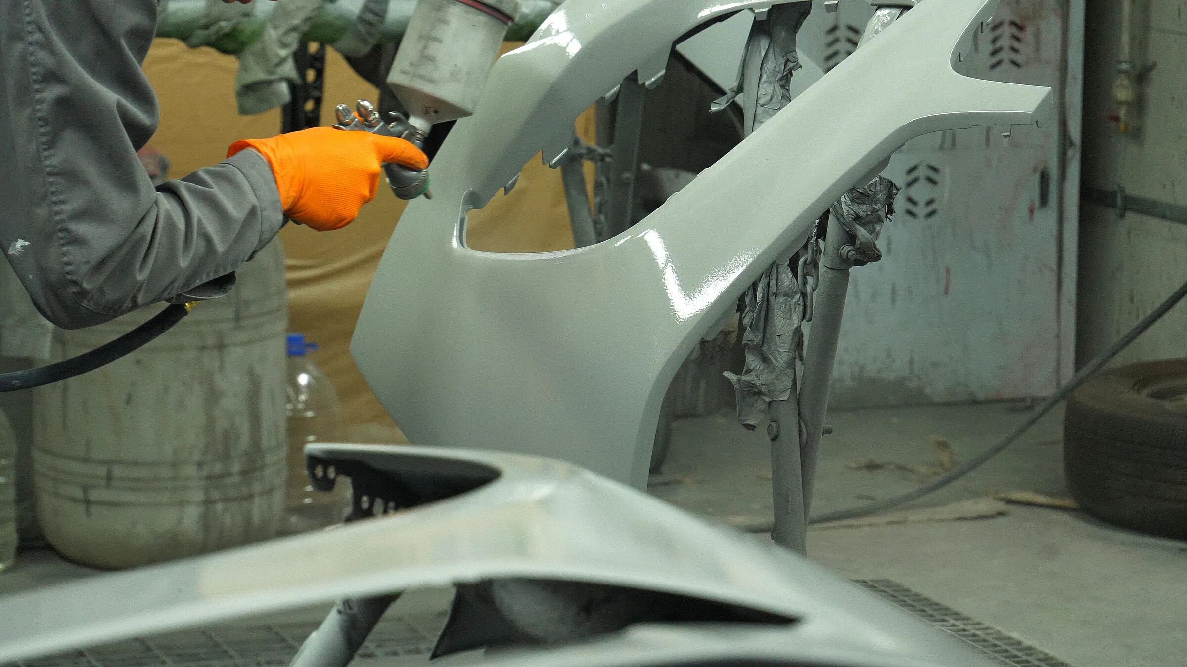 Détail d'une pièce de carrosserie automobile en cours de peinture en atelier.